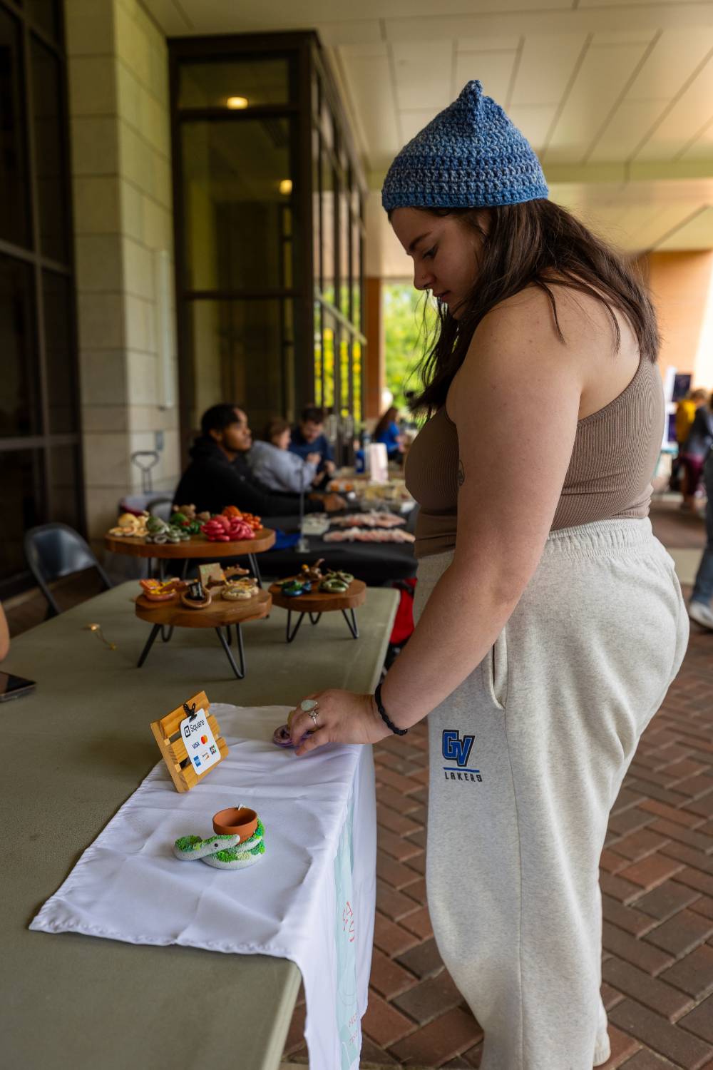 Student looks at display wearing Grand Valley pants during Student Small Business Market.
